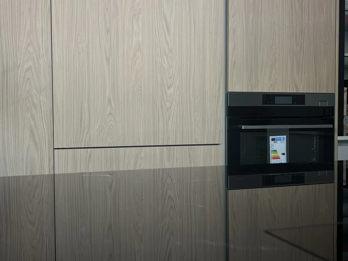 Grifflose Küchenfront in heller Holzoptik mit eingebautem AEG Backofen